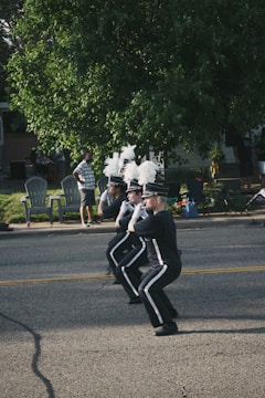 Middle school drumline members in uniform performing on the field with focused expressions.