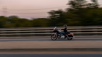 A motorbike rider wearing a helmet cruising along a scenic road.