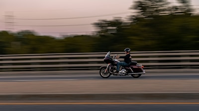A motorbike rider wearing a helmet cruising along a scenic road.