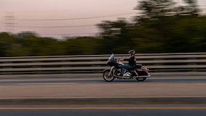 A happy rider cruising a Yamaha cruiser motorcycle along a coastal highway.