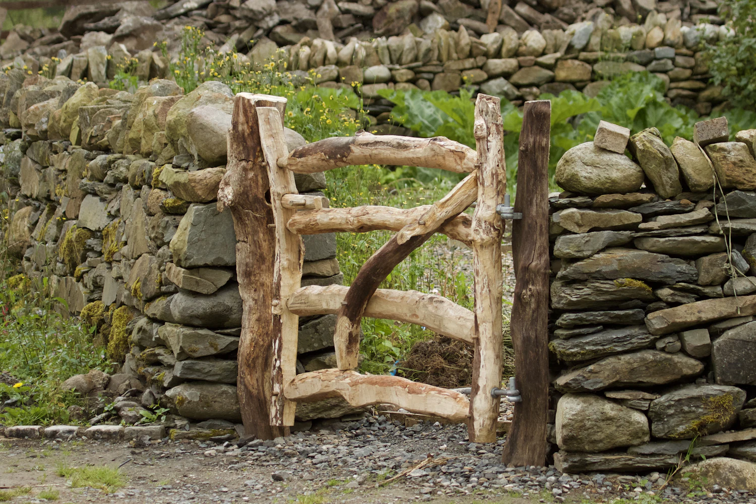 A wooden gate set into an old stone wall in green countryside