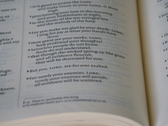 A close-up view of a book page displaying printed text, featuring numbers and passages. The focus is on lines of text, with some words in bold or italics, likely from a religious or spiritual book.