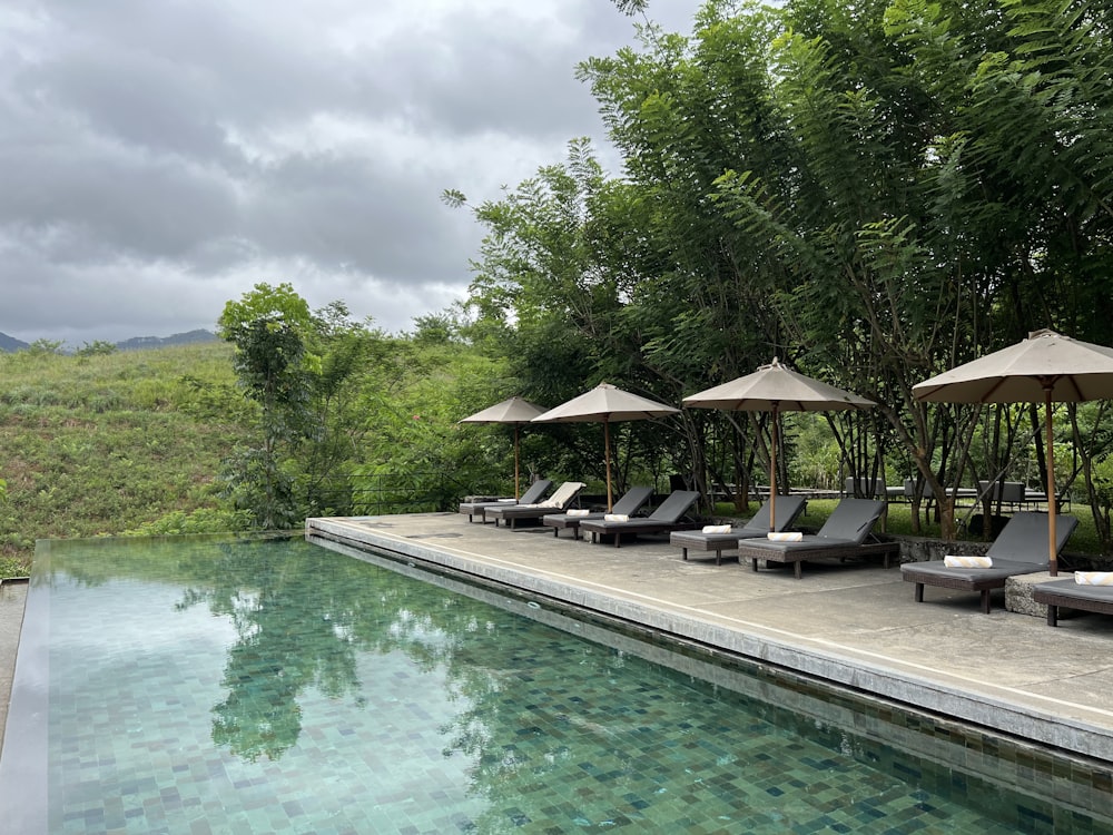 a pool with chairs and umbrellas by it