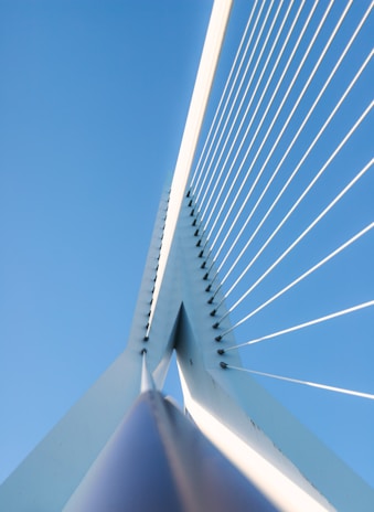 A panoramic view of a massive cable-stayed bridge under construction against a clear blue sky.