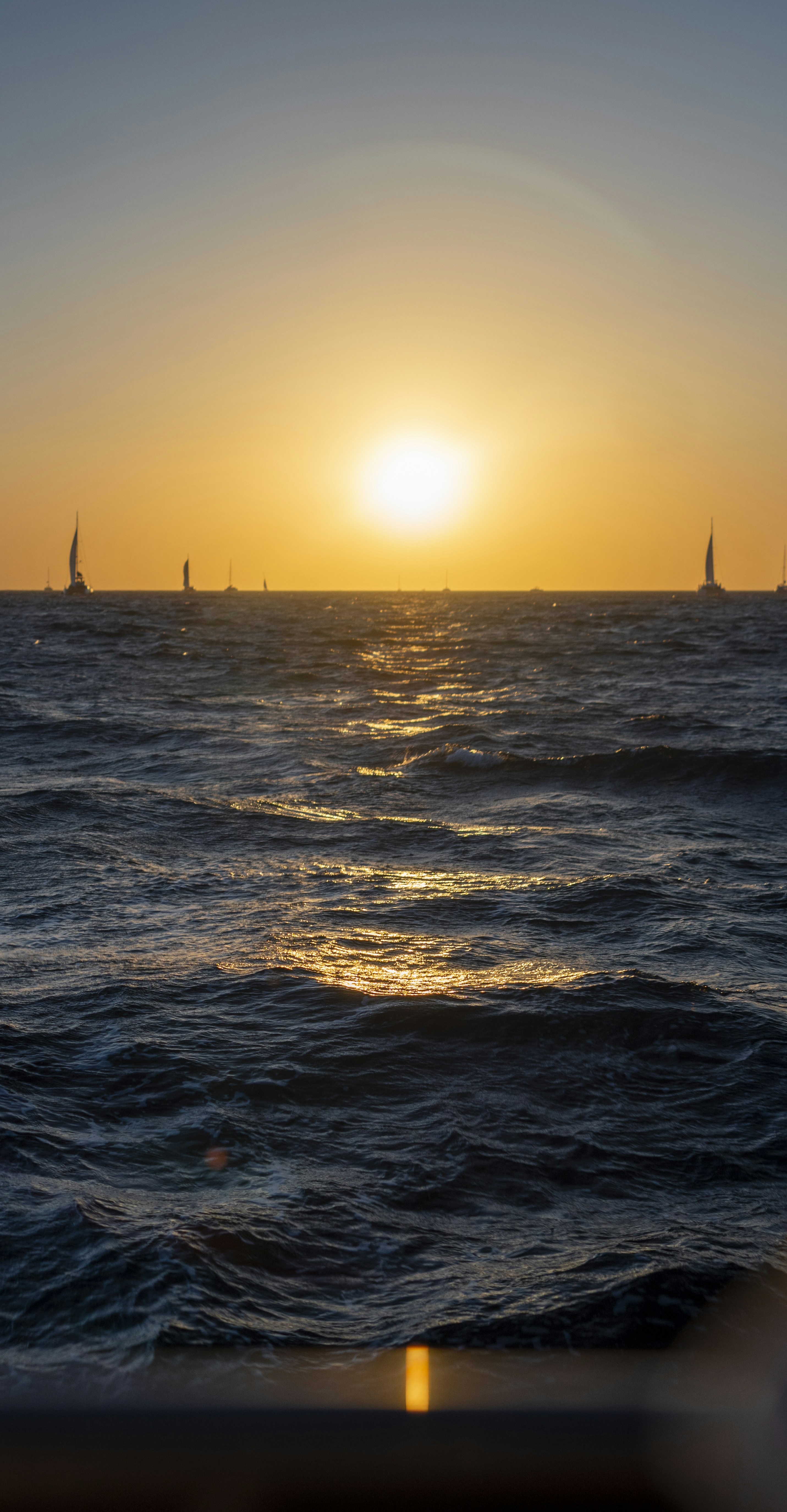 a body of water with boats in it and the sun setting
