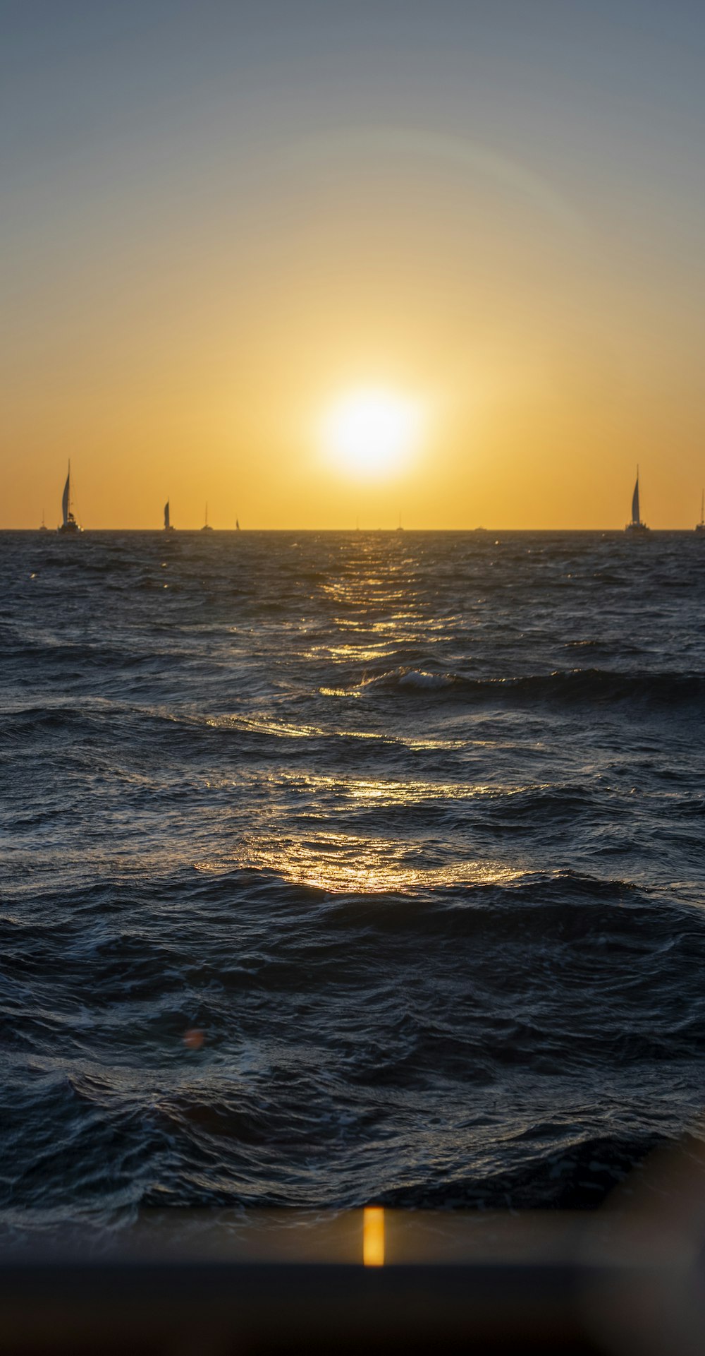 a body of water with boats in it and the sun setting