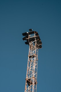 Close-up of a transmission tower frame under construction against a clear blue sky.