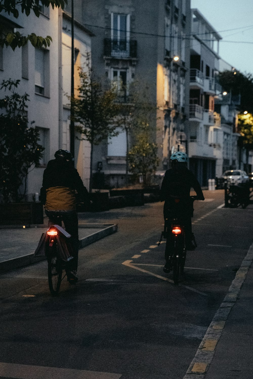 a couple of people ride bikes down a street