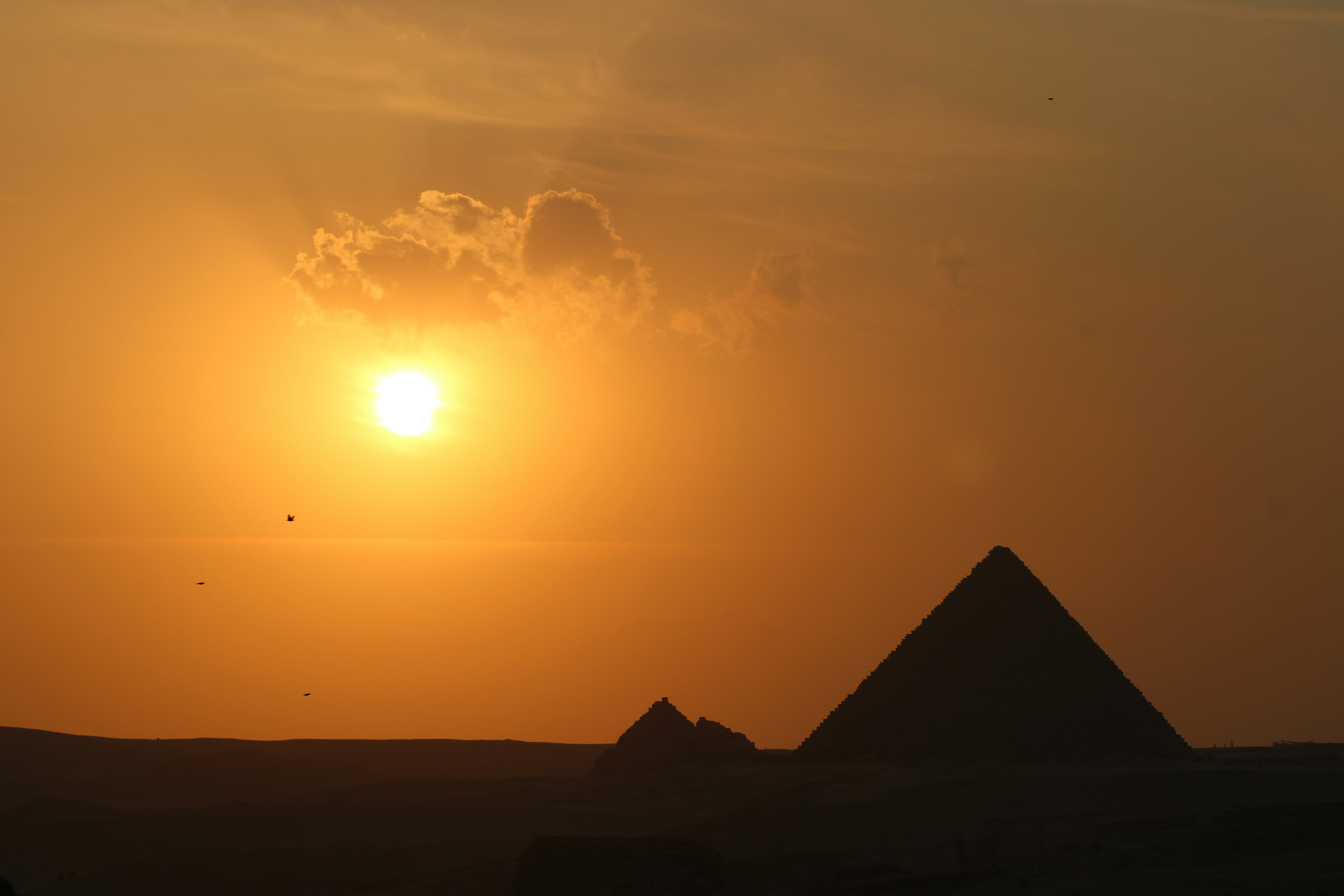 A pyramid with the sun in the background