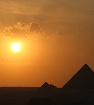 a pyramid with the sun in the background