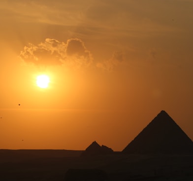 a pyramid with the sun in the background