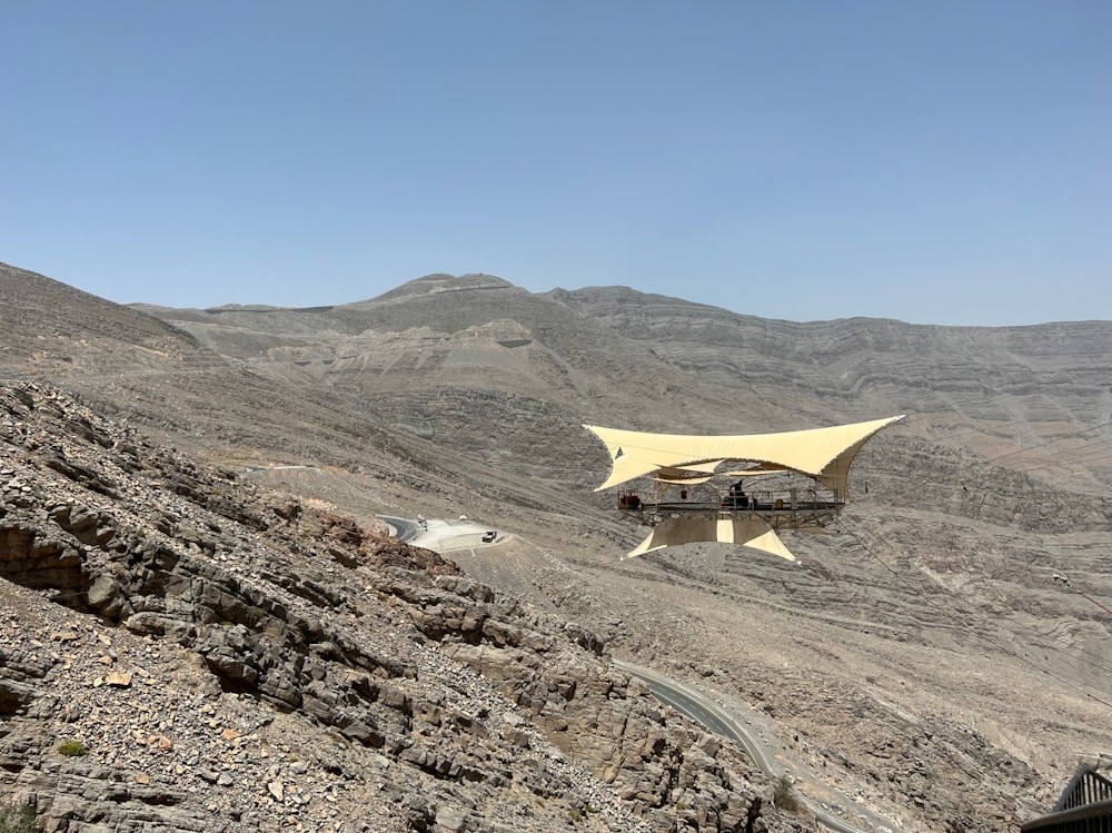 a yellow airplane flying over a rocky landscape