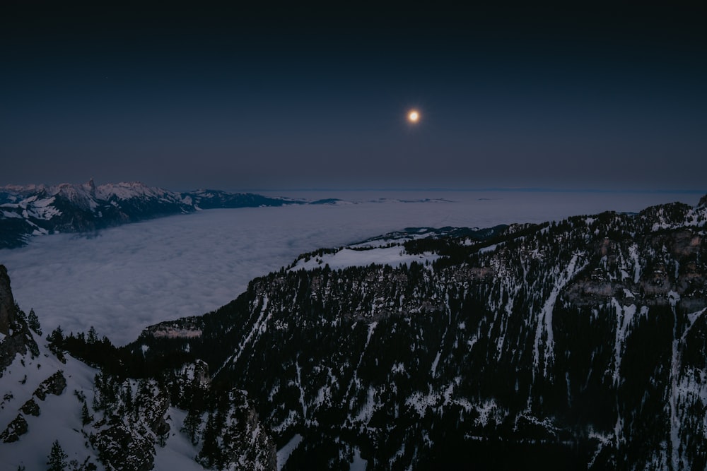a snowy mountain with the moon in the sky