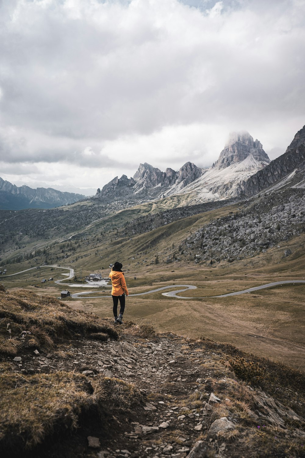 a person standing on a rocky hill with mountains in the background