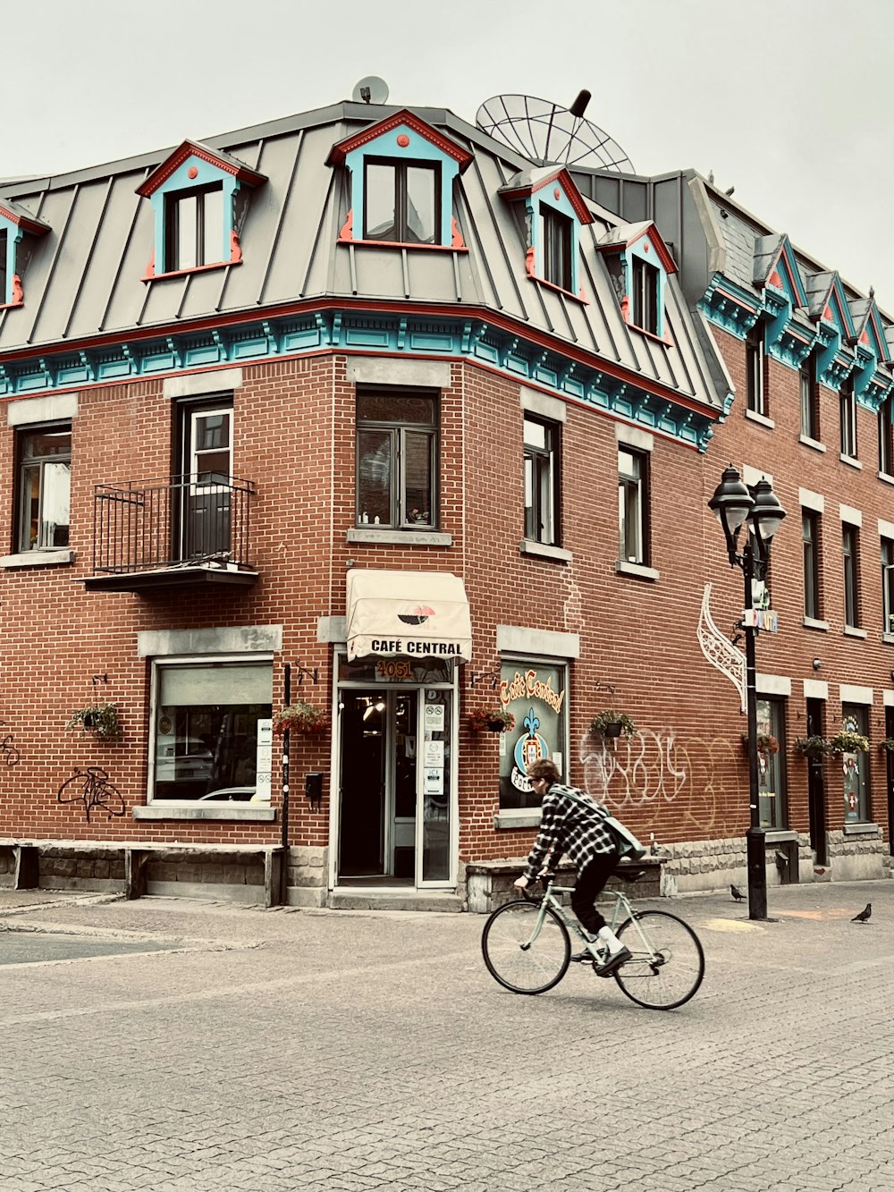 a man riding a bike past a tall brick building