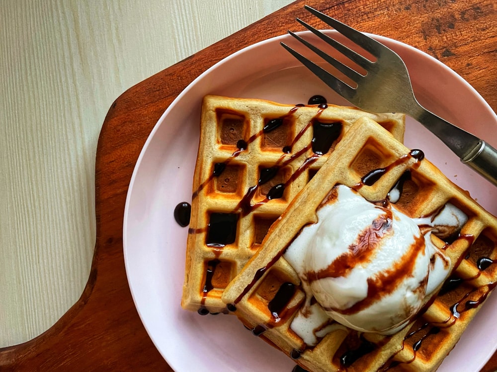 a plate of waffles with syrup and a fork