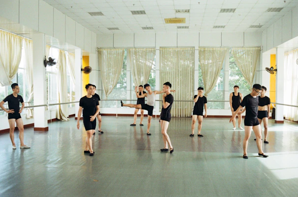Children in a bright studio practicing dance steps with a patient instructor guiding them.