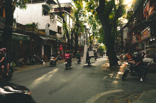 A busy Hanoi street filled with vibrant green trees along the road.