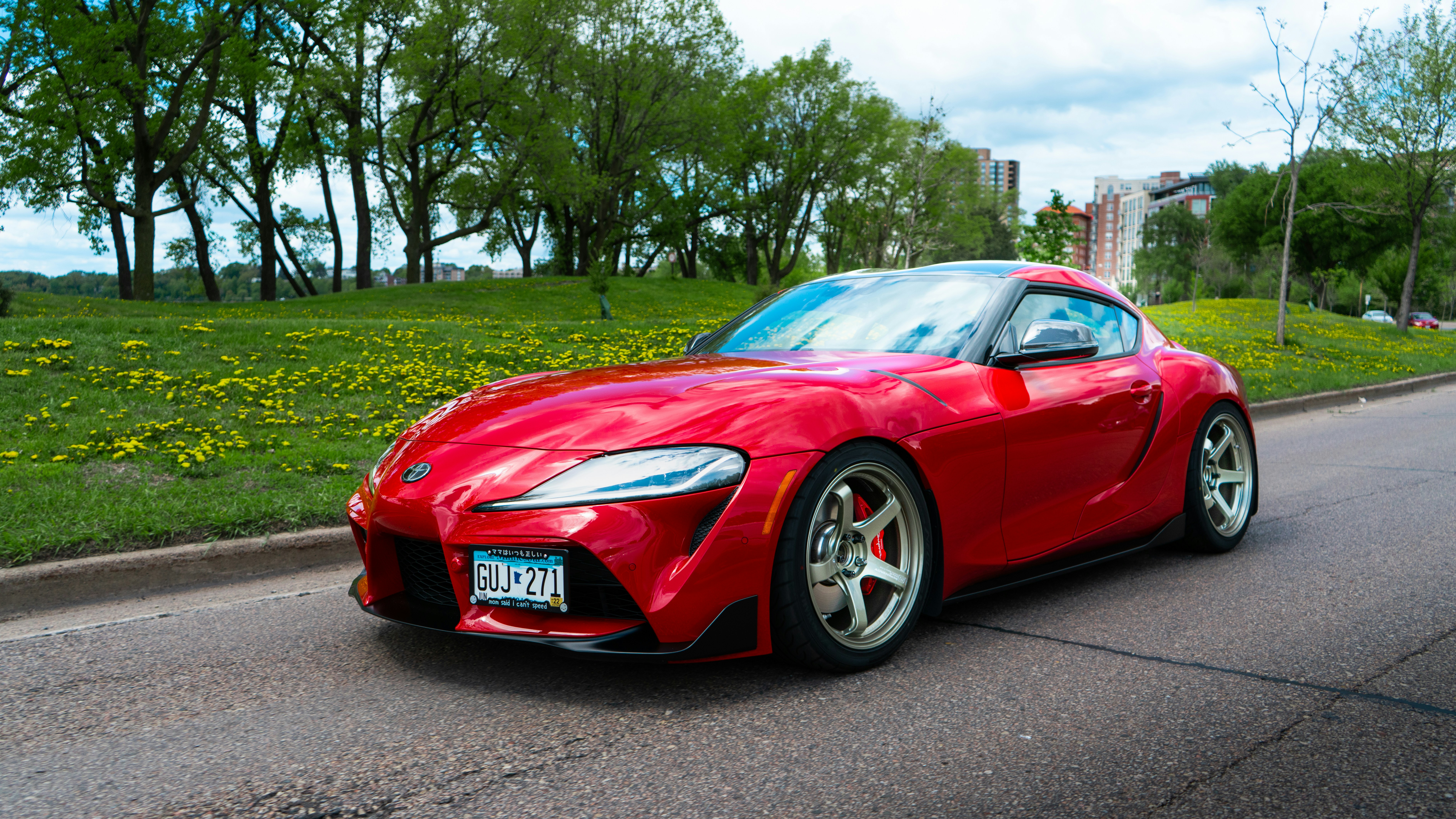 a red sports car parked on a road with trees and grass