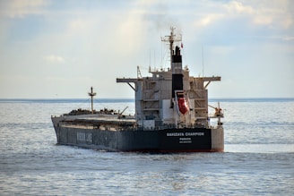A large oil tanker sailing smoothly on the open sea under a clear sky.