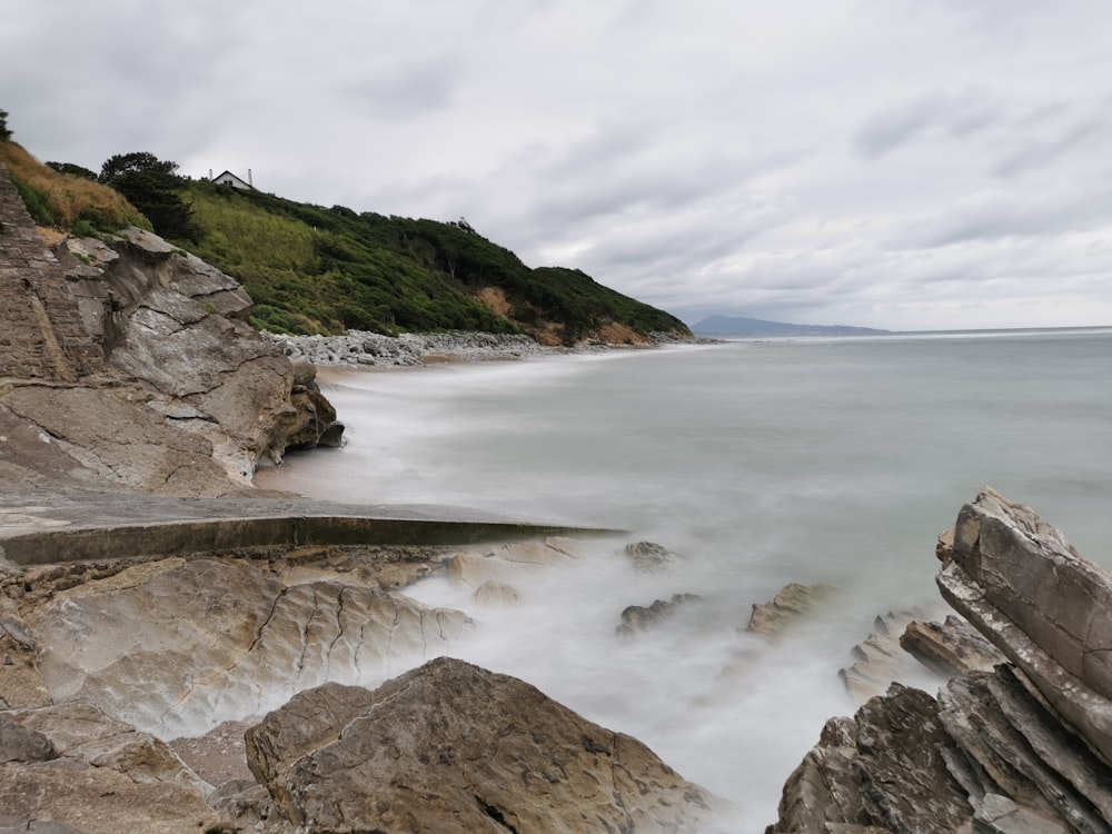 a rocky beach with a hill in the background