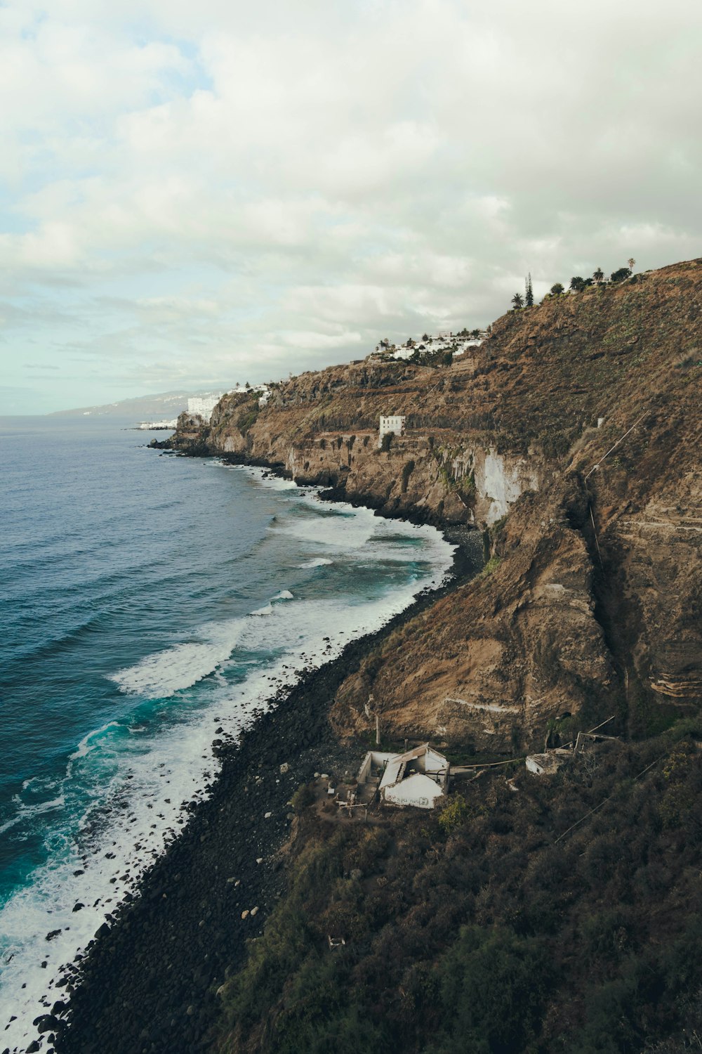 a cliff side with a body of water and a building on it