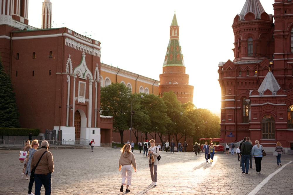 a group of people walking in a plaza with buildings in the background with Red Square in the background