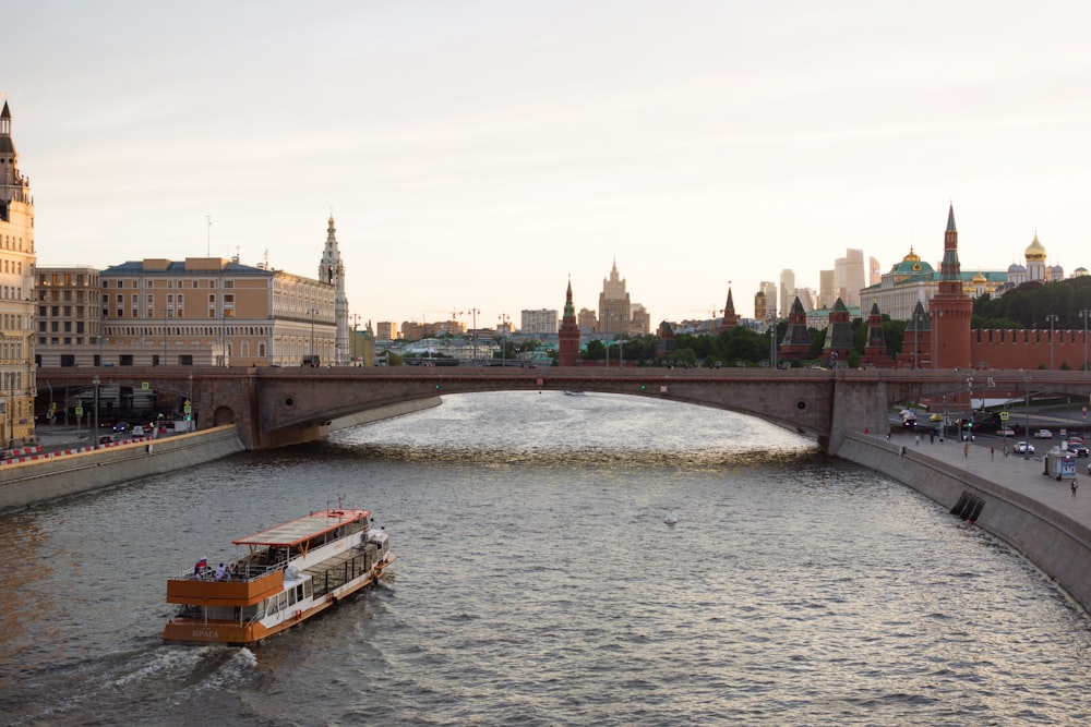 a boat on a river with a bridge and buildings in the background