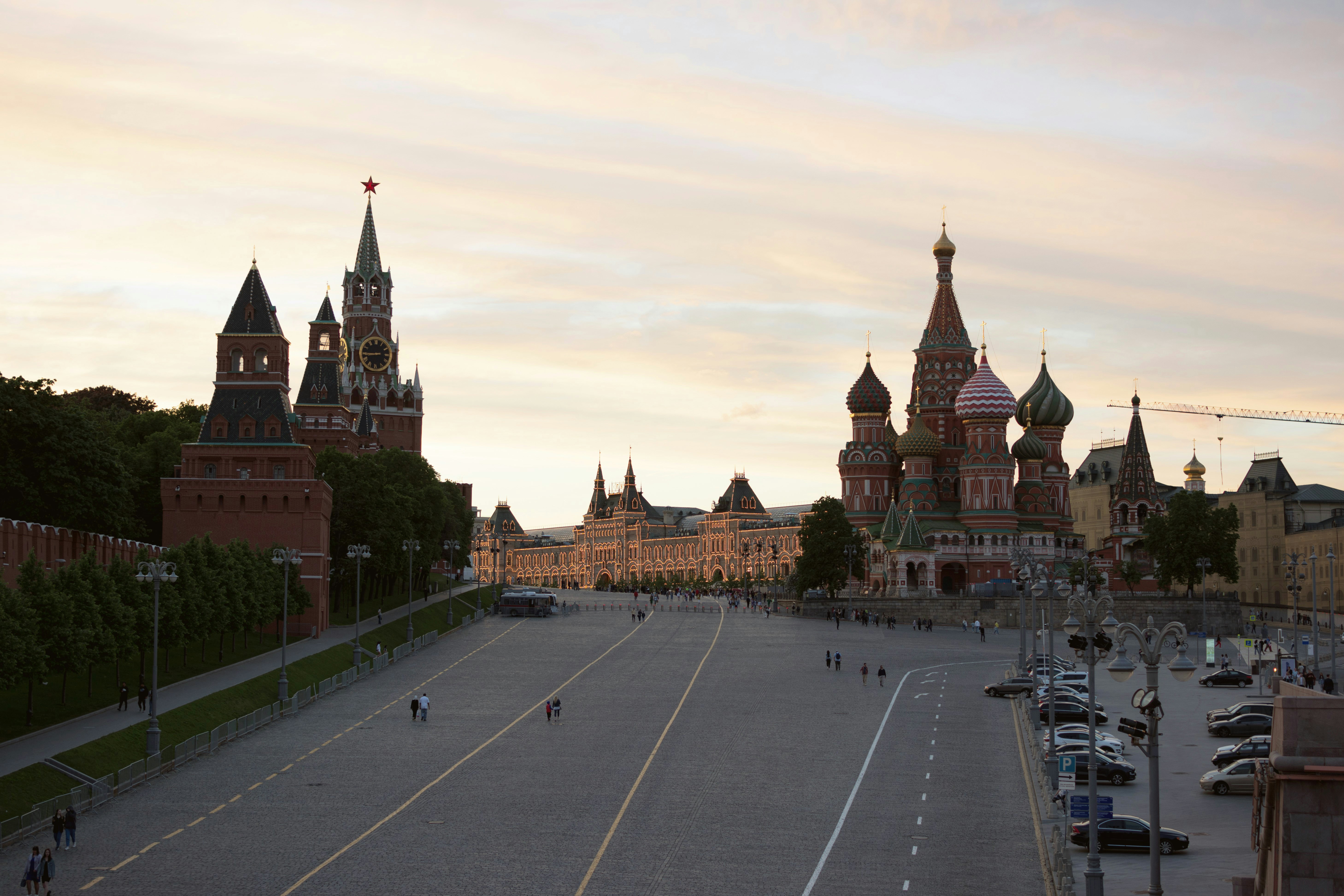 a road with cars and buildings along it with Red Square in the background