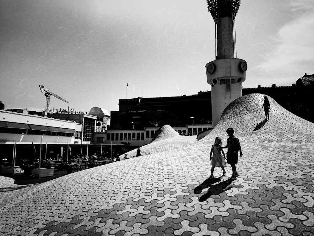 a group of people walking on a brick road next to a large tower