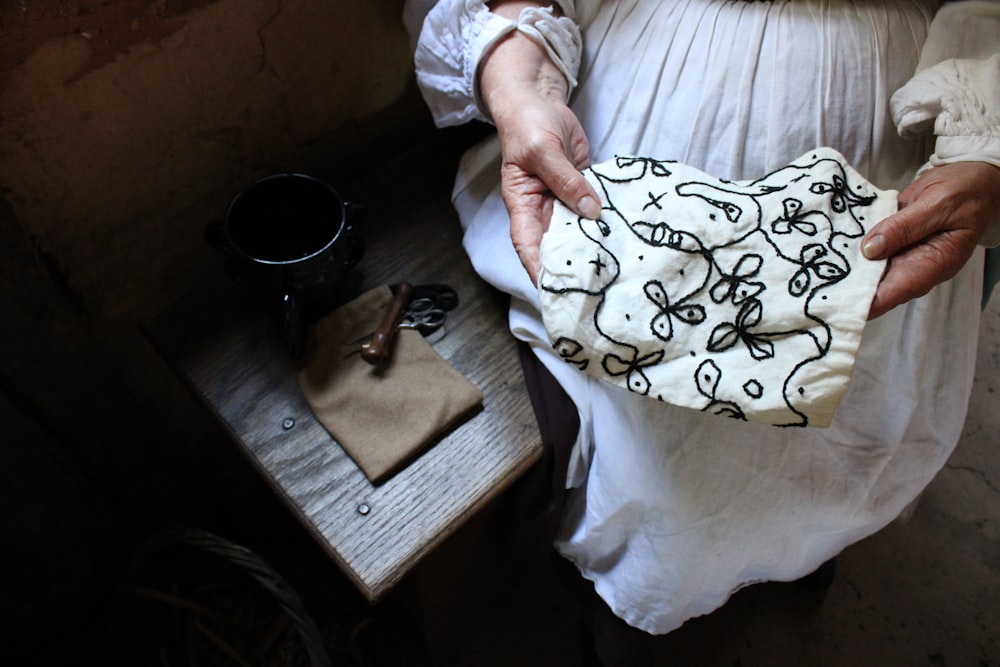 a person holding a white sheet over a wooden box with a white cloth