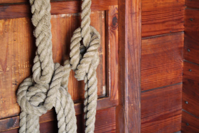 An elegant rope tied in a decorative knot on a rustic wooden table.