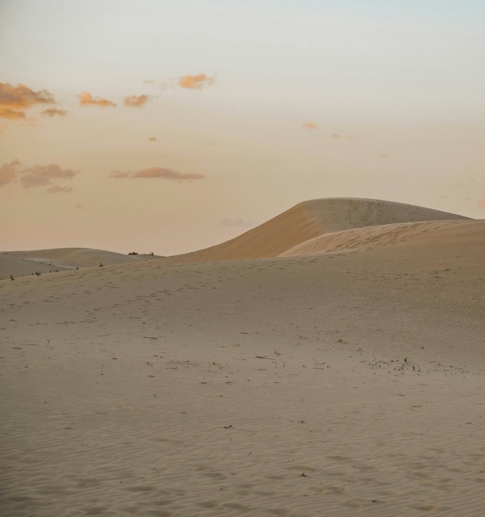 a sandy beach with hills in the background