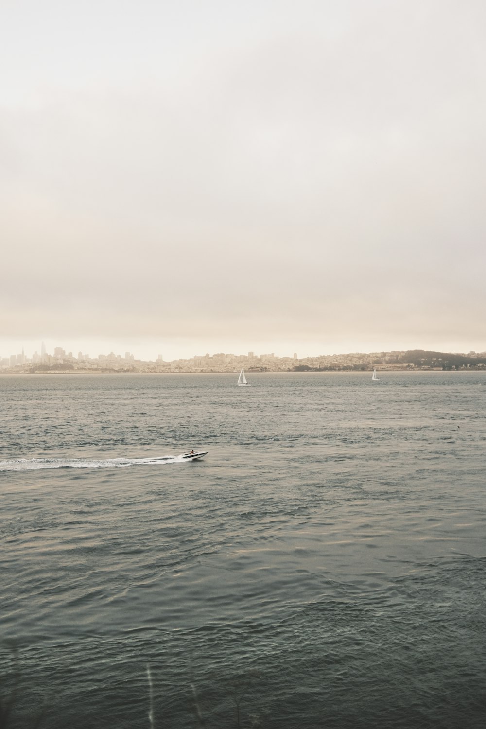 a body of water with boats in it and a sailboat in the distance