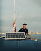 Marine DIY solar setup on a boat deck with waterproof storage boxes and connected solar panels under bright sunlight.