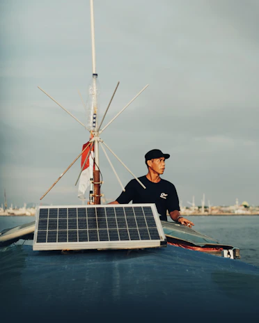 Close-up of a member adjusting solar panels on their electric yacht deck under bright blue skies.