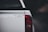 The back of a white vehicle with a humorous sticker that reads 'tell your dog i said hi'. The bright red tail light contrasts against the dark blurred background.