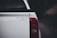 The back of a white vehicle with a humorous sticker that reads 'tell your dog i said hi'. The bright red tail light contrasts against the dark blurred background.