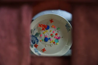 Close-up of a bright, multicolored decorative bowl on a wooden table.