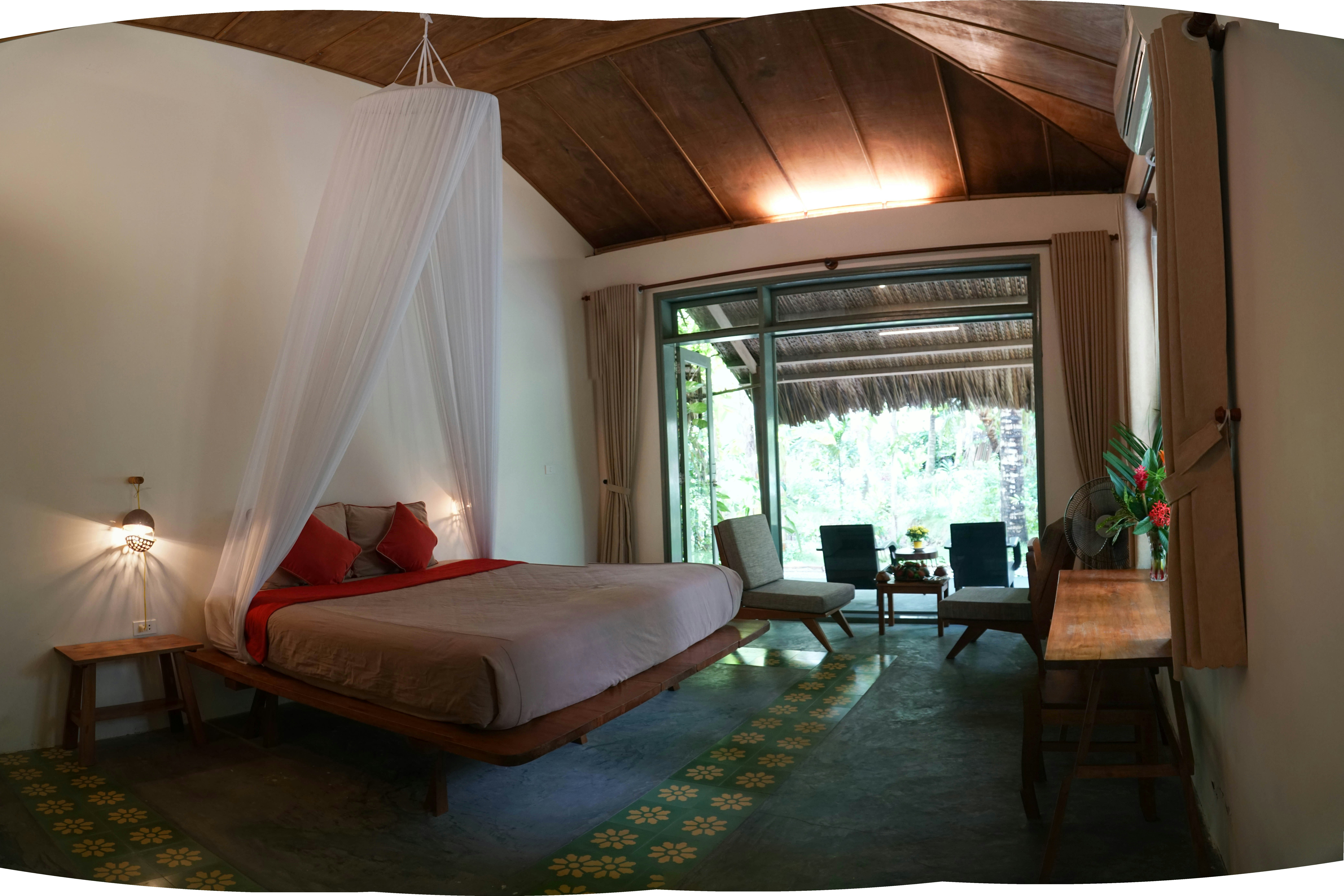 Tropical villa bedroom with wooden ceiling and panoramic jungle view through large windows