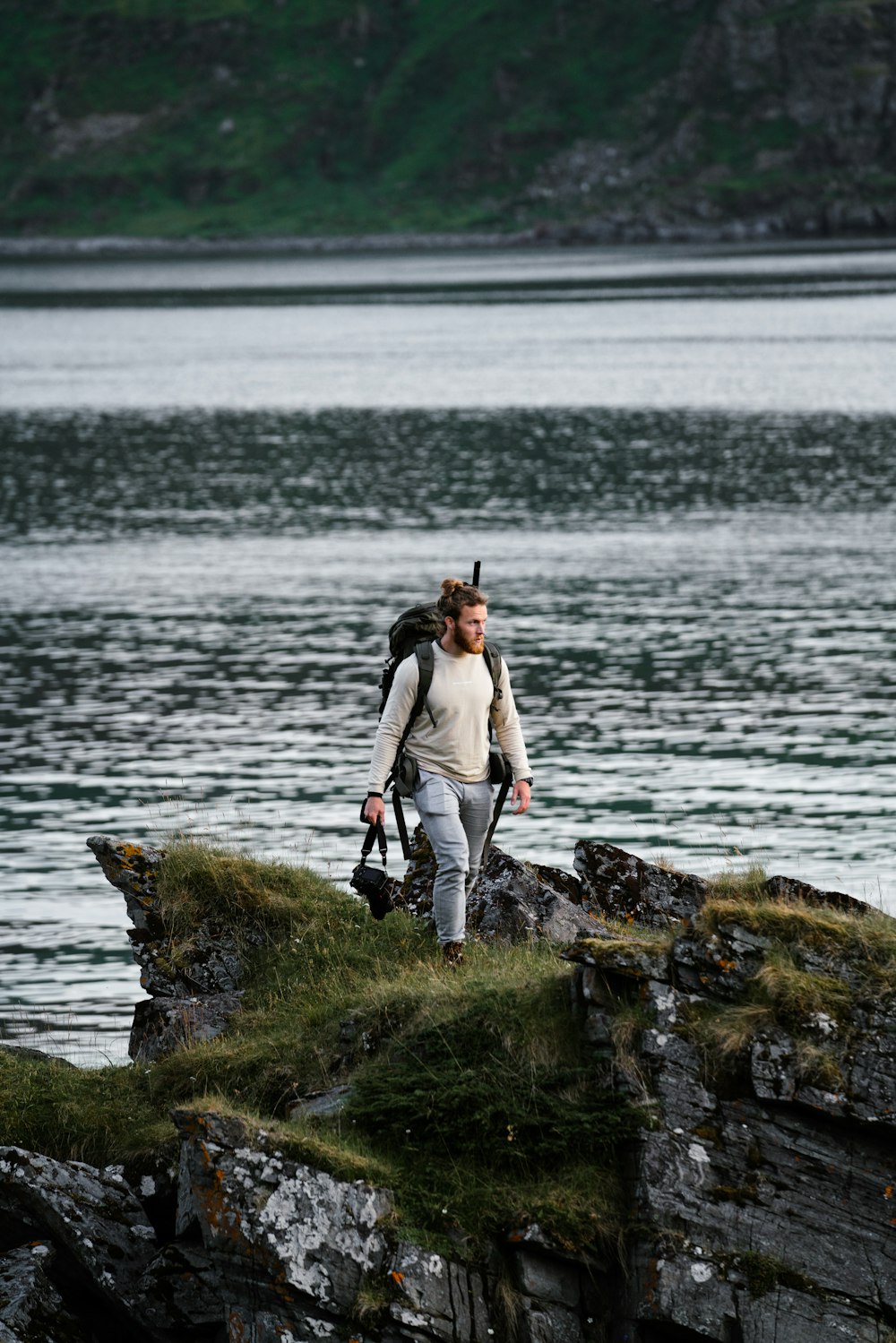 a man standing on a rock by a body of water