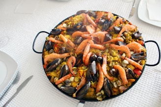 A vibrant paella dish filled with fresh seafood and colorful vegetables in a large pan.