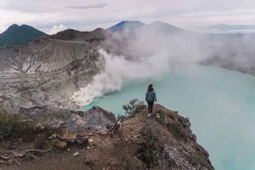 a person standing on a rocky cliff overlooking a body of water