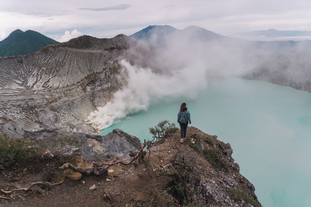 a person standing on a rocky cliff overlooking a body of water