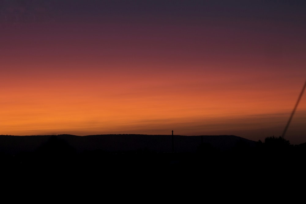 a sunset over a hill