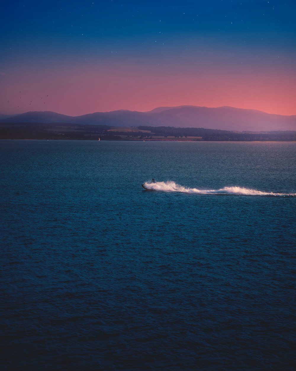 a body of water with a boat in it and mountains in the background