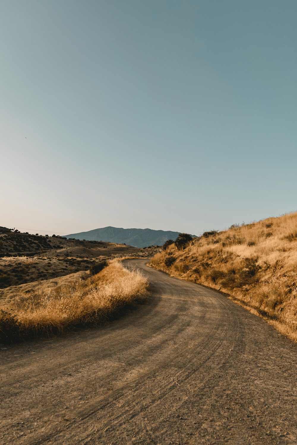 a dirt road with hills on either side of it