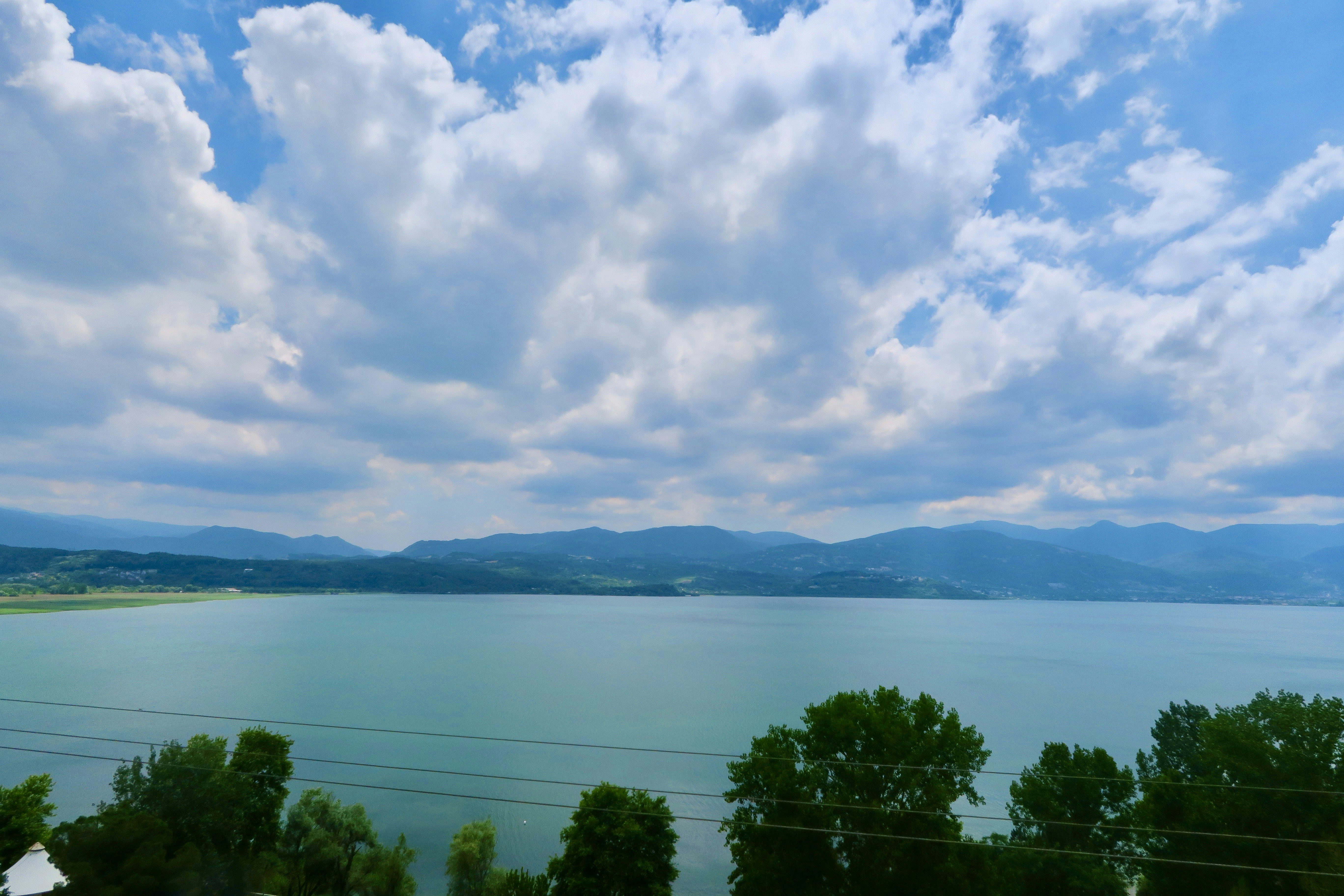 a body of water with trees and mountains in the background, 