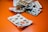 A collection of various blister packs containing different types of tablets and capsules are spread out on an orange surface. The blister packs are partially empty, with some tablets missing.