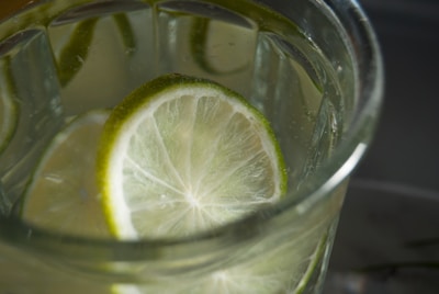 Close-up of a chilled, translucent bottle with refreshing liquid inside, surrounded by fresh fruit slices.